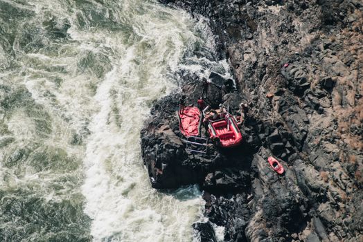 Adventure scene of red rafting gear on rocky riverside, from above.