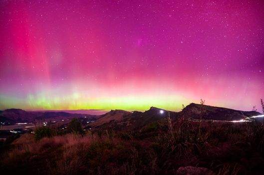 Stunning display of the Aurora Australis with vivid pink and green hues over Canterbury's landscapes at night.