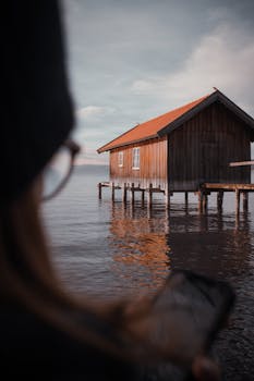 An inviting boathouse on Ammersee, Bavaria, captured at sunset with warm tones and serene reflections.