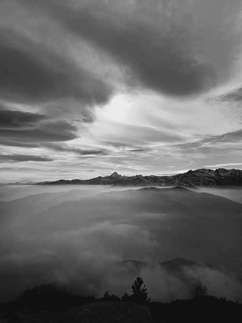 Free Monochrome view of mountains shrouded in clouds under dramatic skies. Perfect for winter themes. Stock Photo