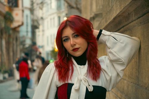 Free A stylish woman with red hair poses elegantly on a bustling street in Istanbul, showcasing urban fashion. Stock Photo