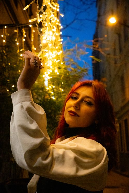 Free Chic young woman with red hair posing in a dimly lit Istanbul alley at night. Stock Photo
