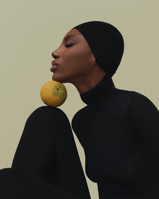 Artistic portrait of a woman balancing an orange on her knee in minimalistic style.