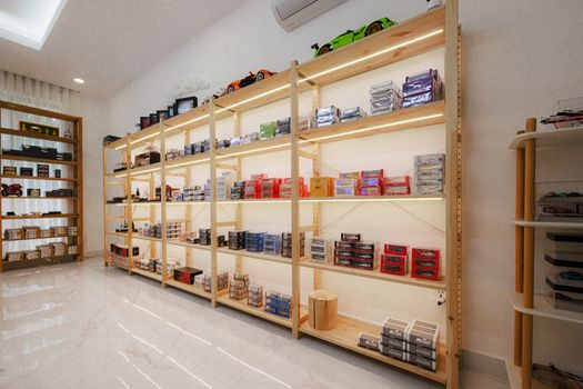 Bright modern display of diecast model cars on wooden shelves in a Phnom Penh store.