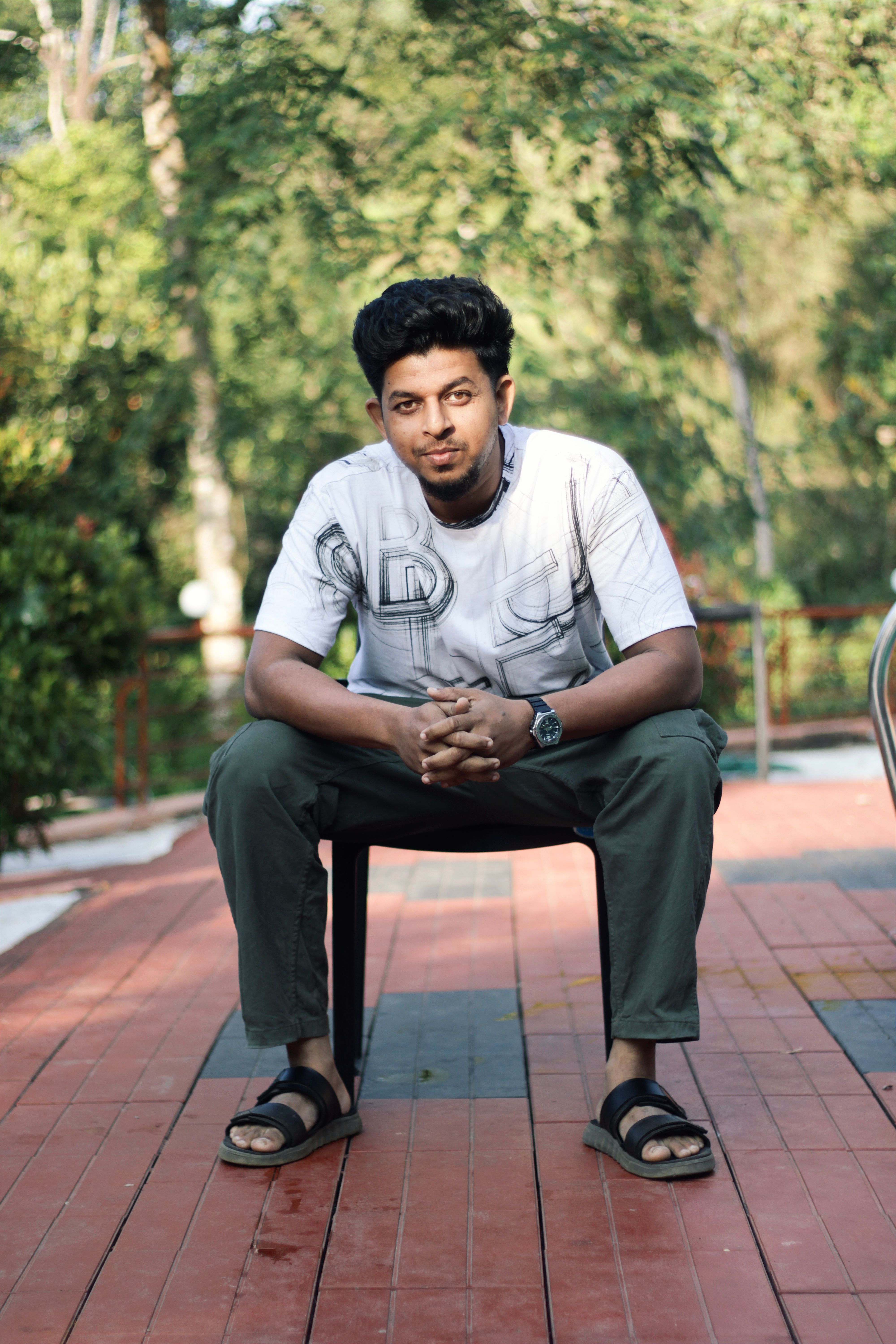 Portrait of a young man sitting on a chair outdoors in Kerala, India.