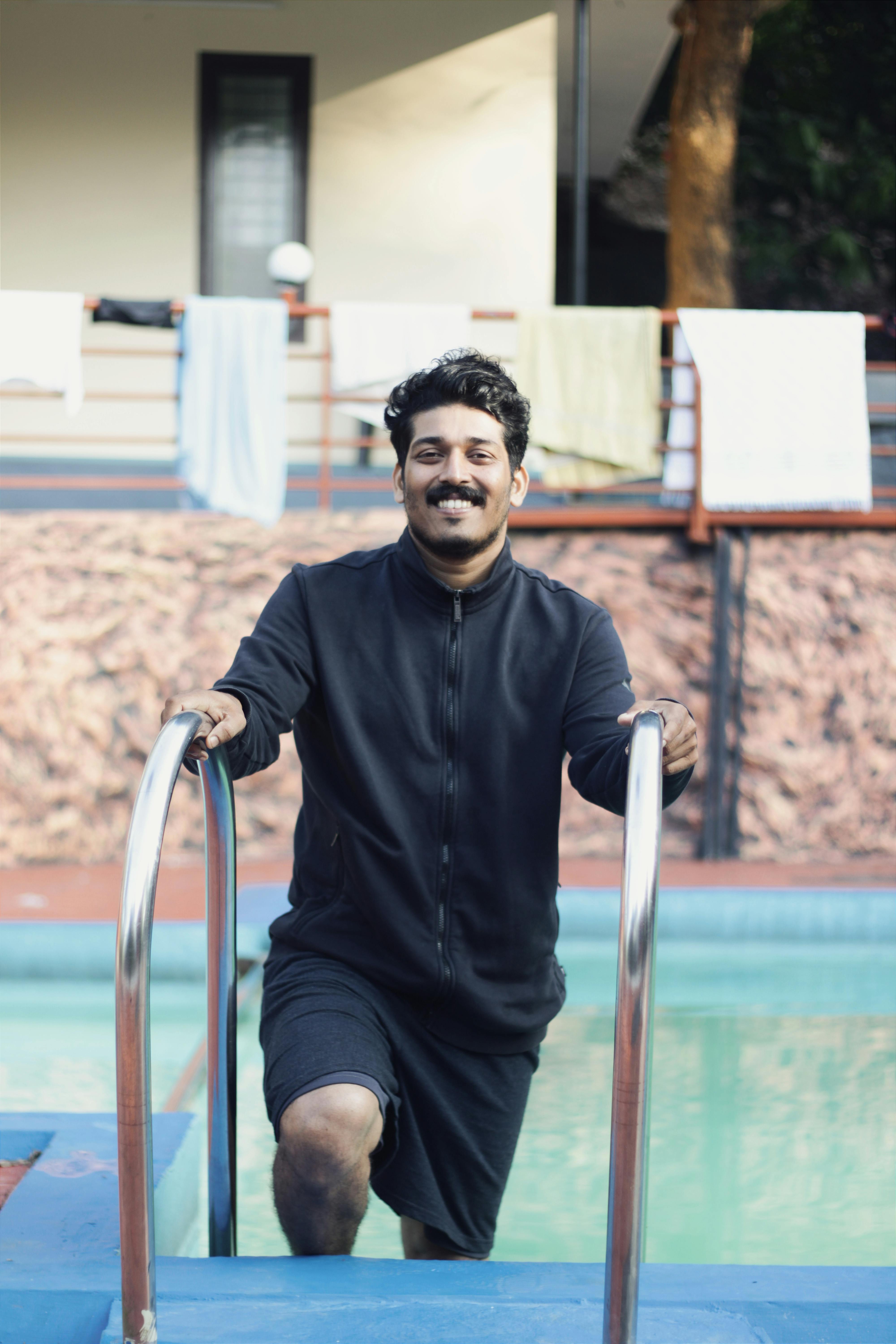 Cheerful young man in casual attire at a resort swimming pool.