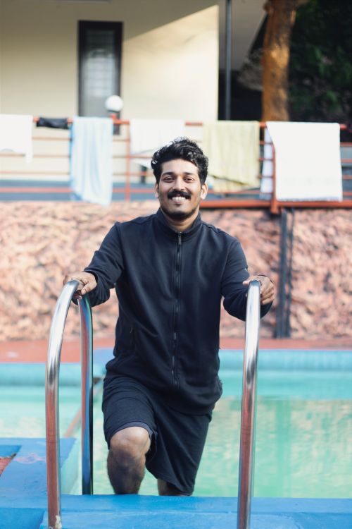 Free Cheerful young man in casual attire at a resort swimming pool. Stock Photo