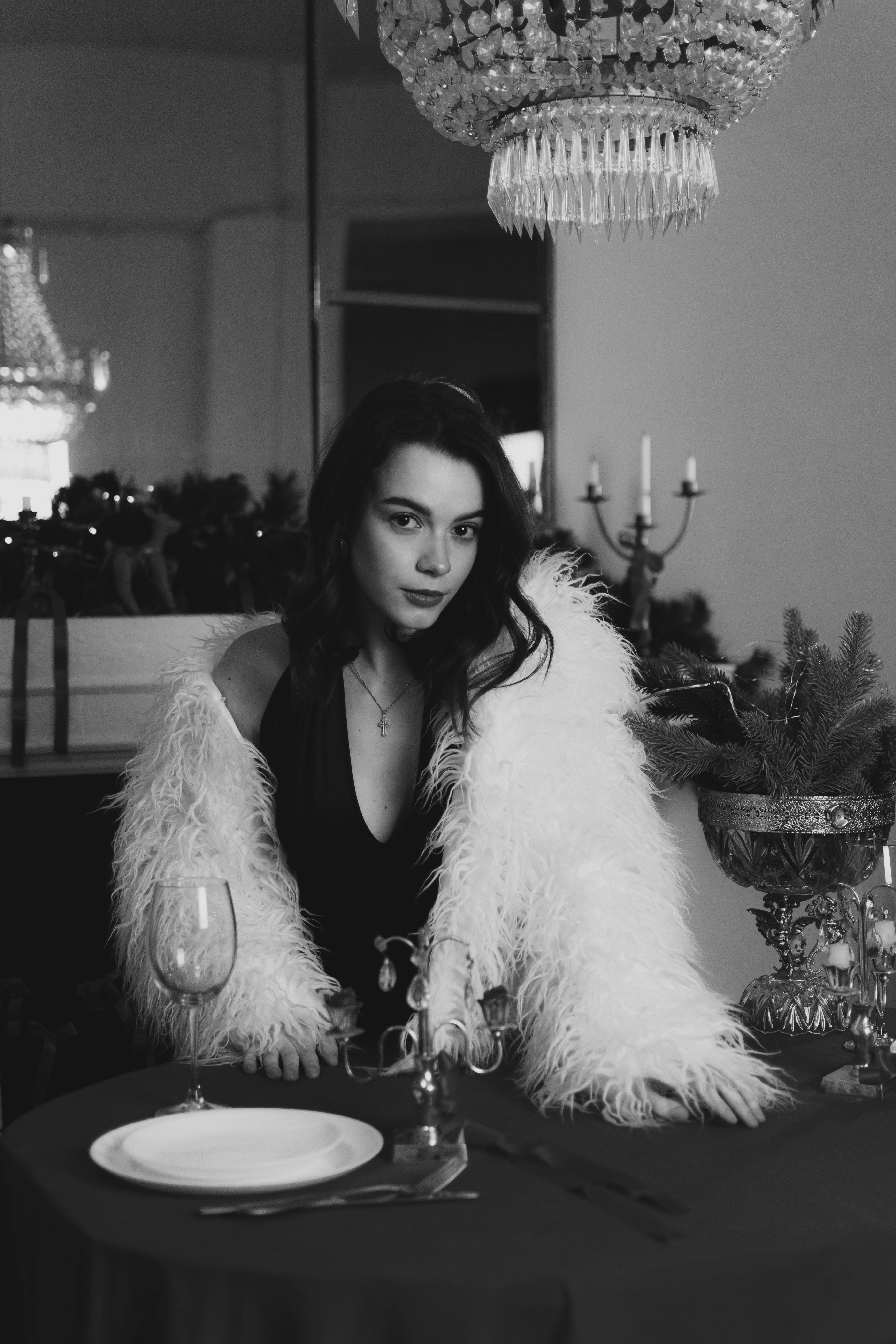 Black and white portrait of a woman in a luxurious dining setting.
