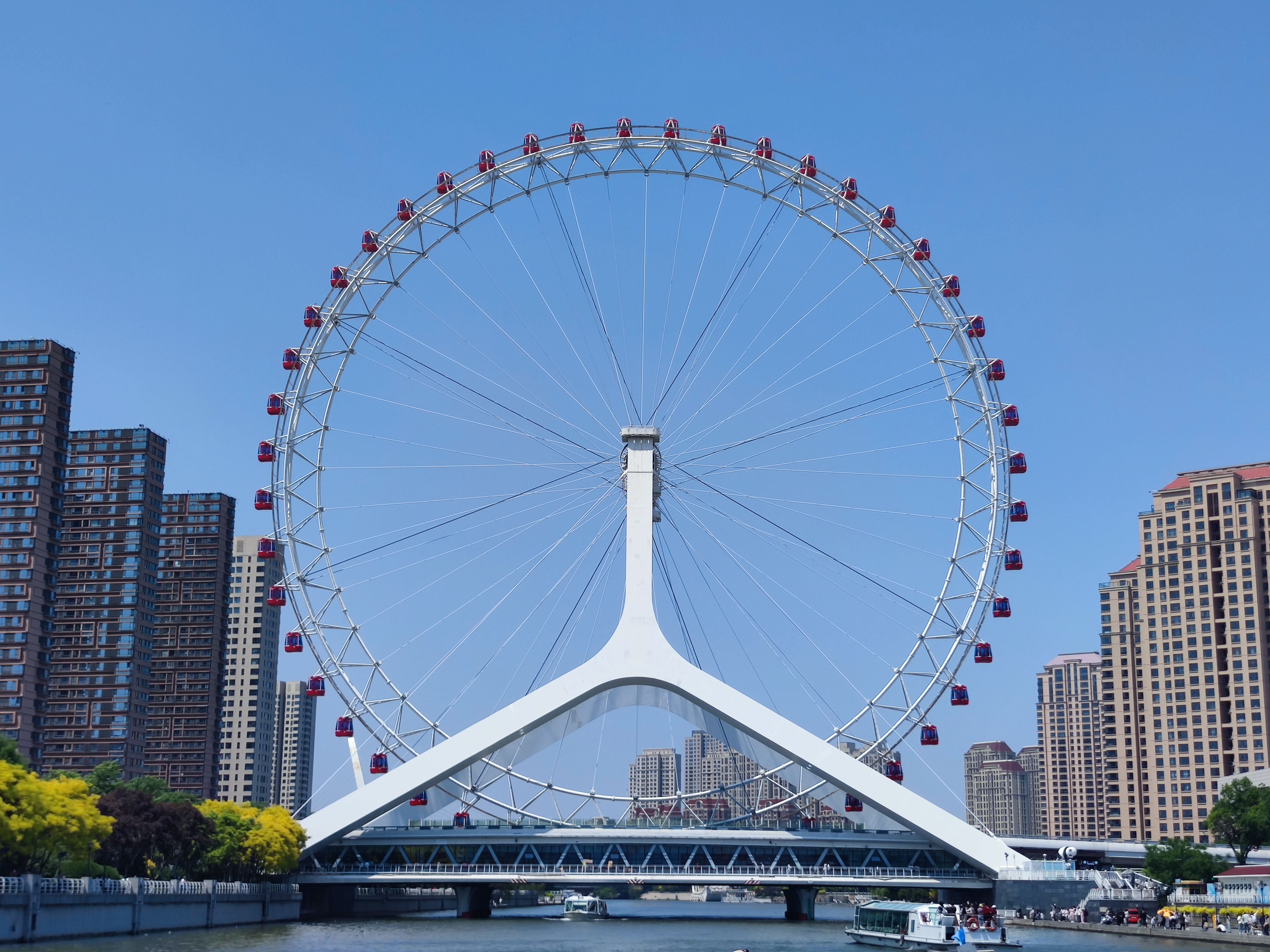 Stunning view of the Tianjin Eye Ferris Wheel spanning the Hai River, with modern cityscape in the background.