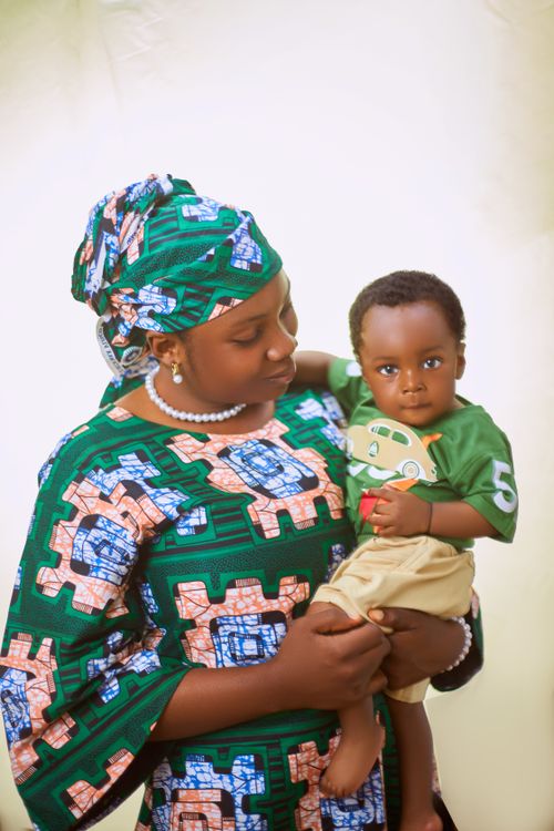 Free A mother lovingly holding her child, both in vibrant African prints. Stock Photo