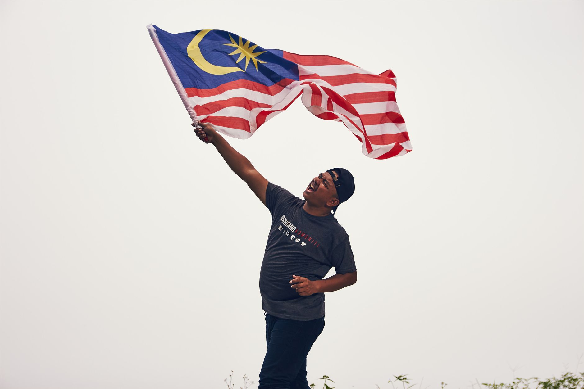 Malaysian supporters holding national flags outside Gelora Bung Karno Stadium in Jakarta at sunset