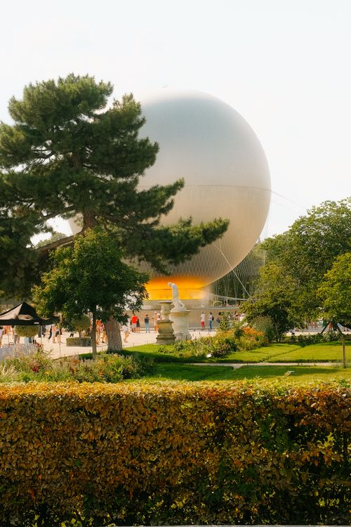 Free Paris hot air balloon floating above lush gardens on a sunny day. Stock Photo