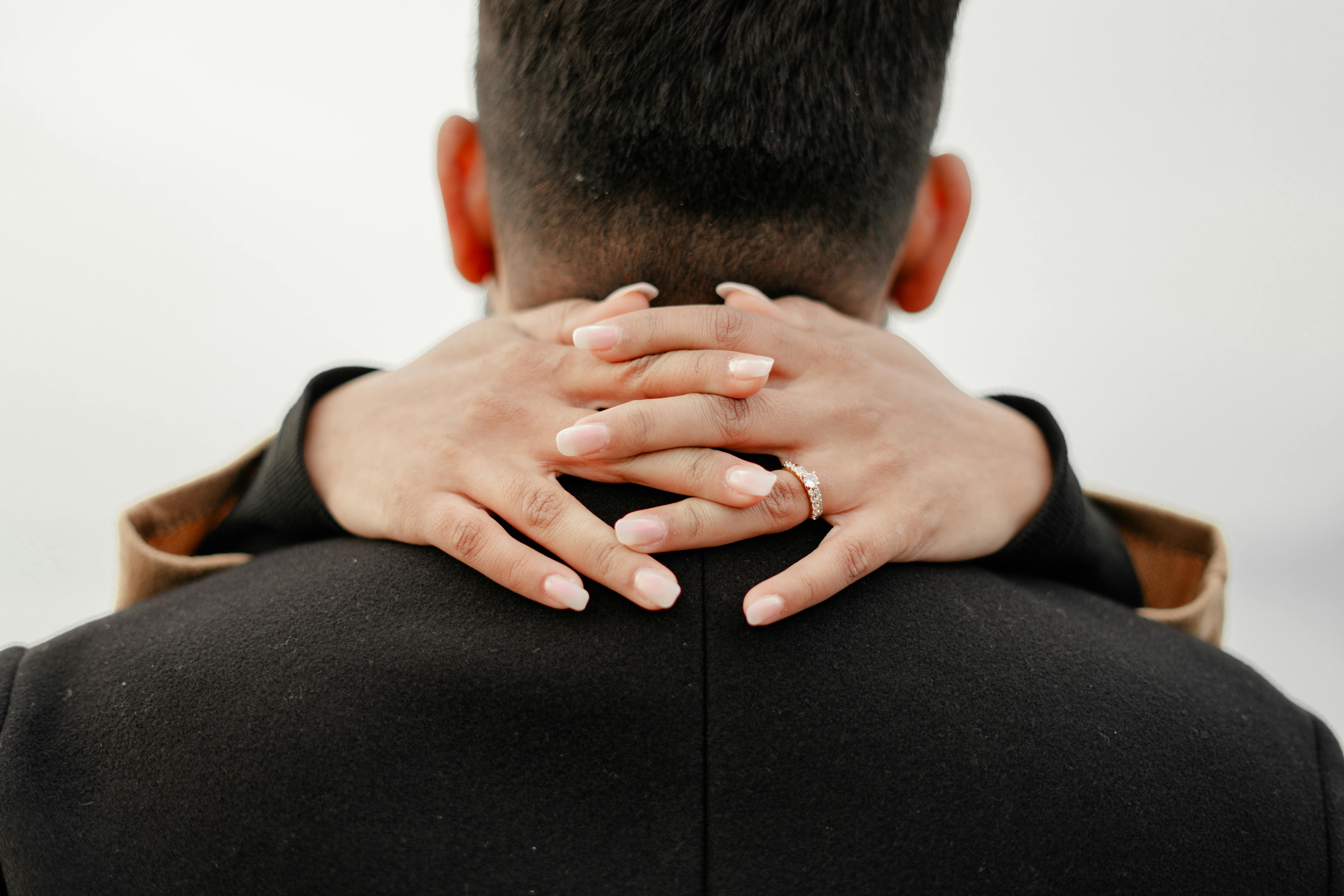 A couple embracing with a focus on hands and engagement ring, conveying love and romance.