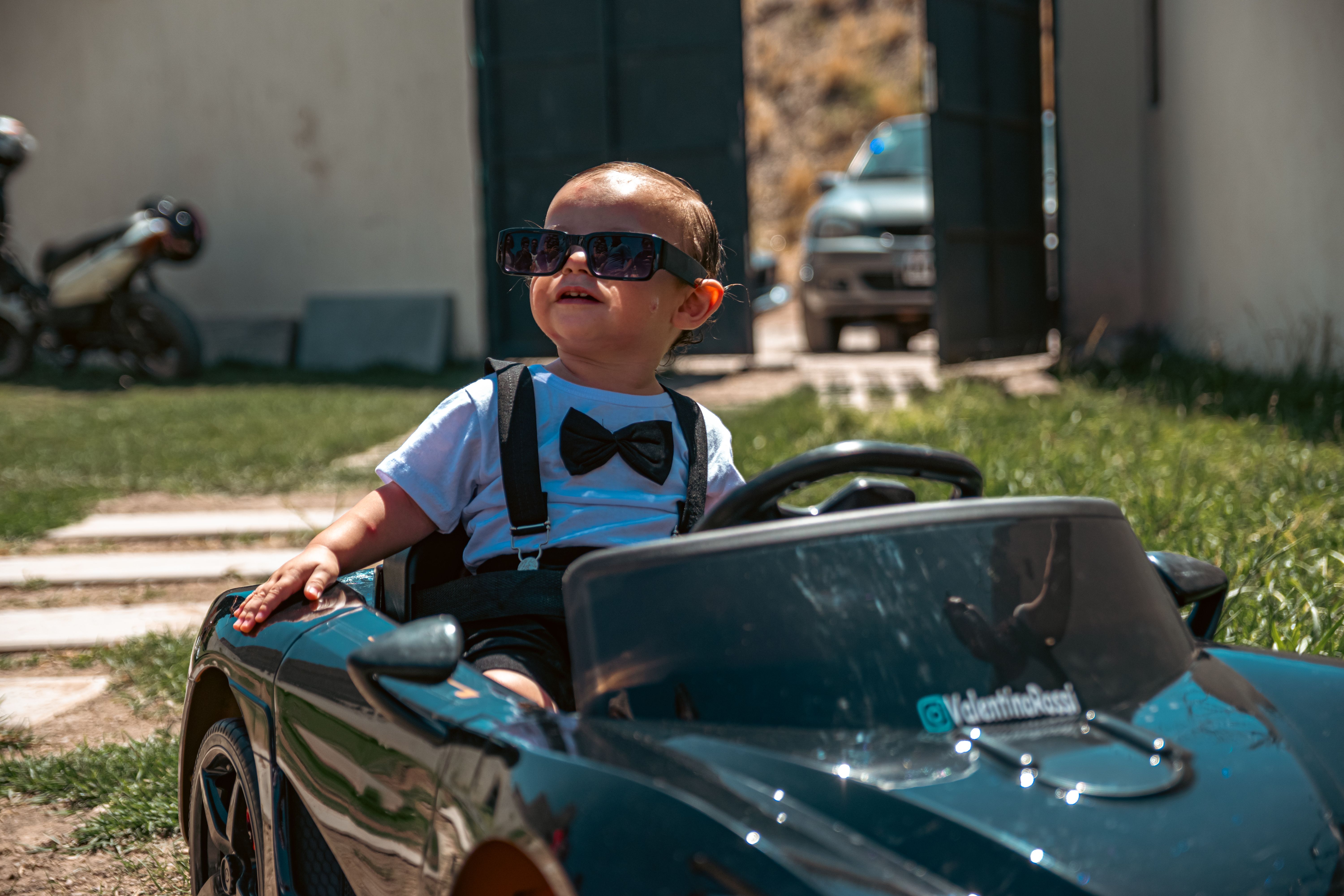 Young child in a summer outfit playing outdoors with a toy car
