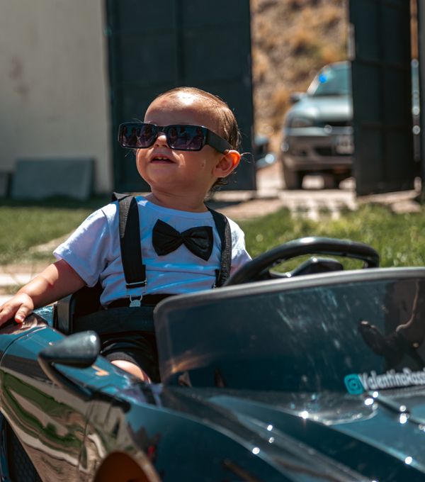 Young child in a summer outfit playing outdoors with a toy car