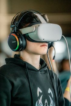 Teenager wearing VR headset and headphones, exploring virtual reality. Immersive technology experience.