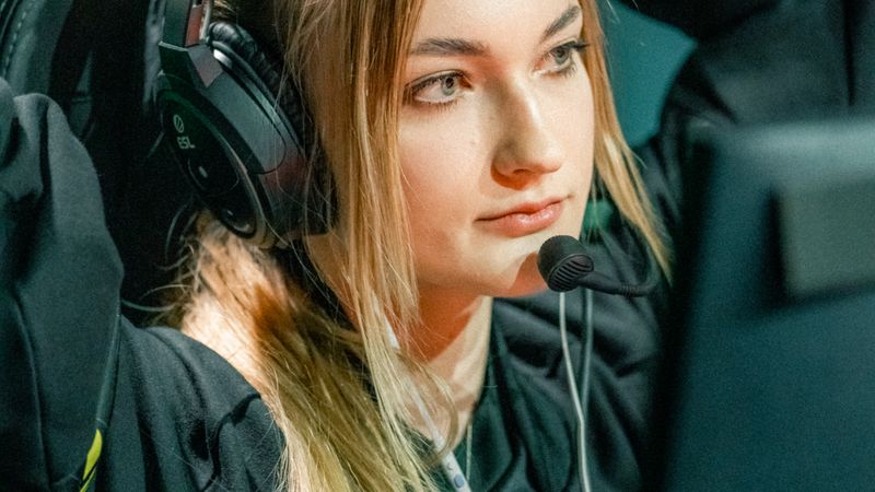 Young female gamer with headset intensely focused during an esports competition.