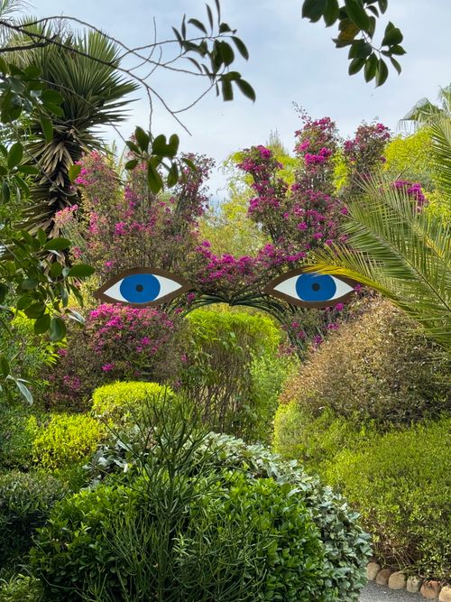 Free Lush Marrakesh garden with artistic eye mural, vibrant flowers, and greenery. Stock Photo