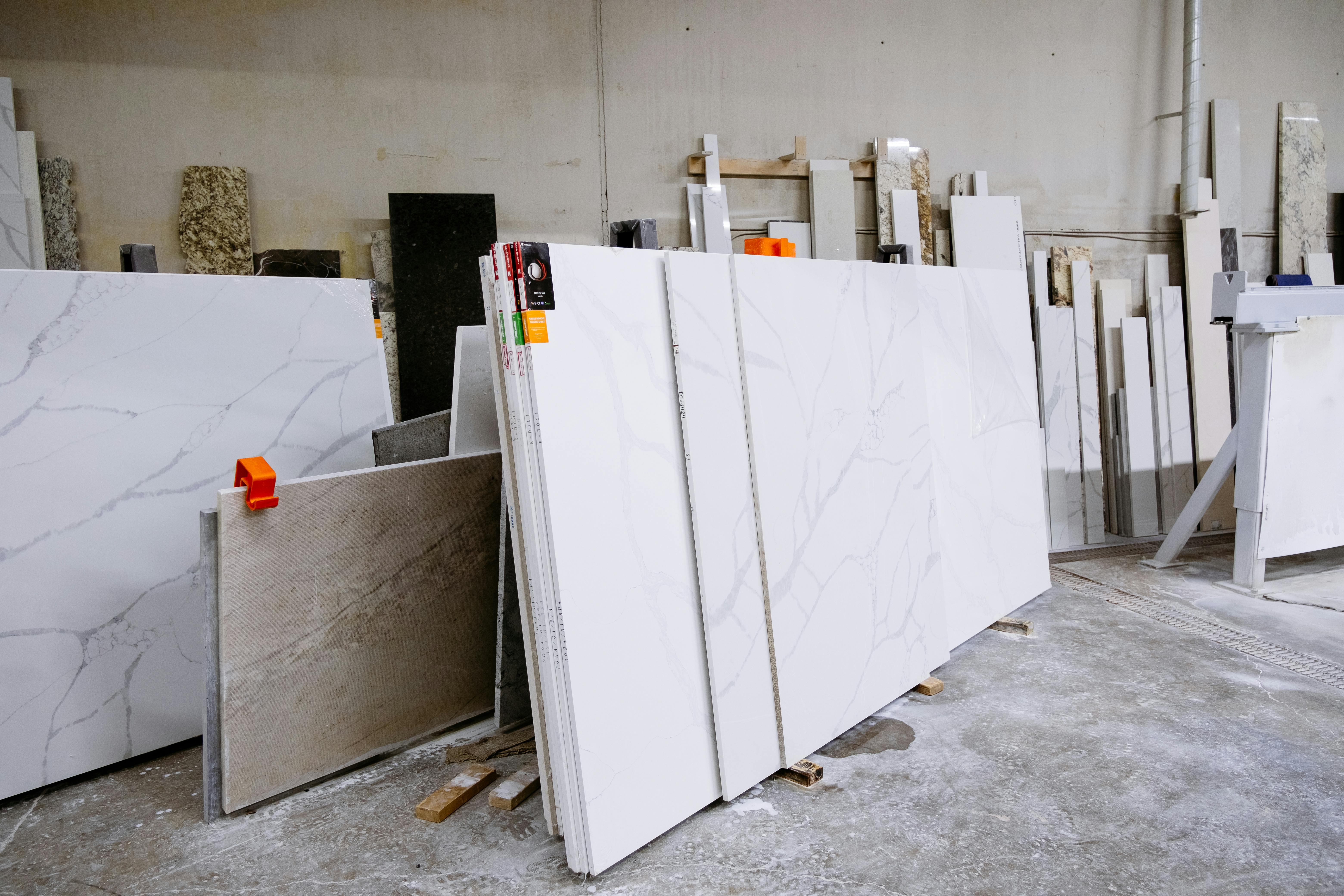 Wide view of granite and marble slabs neatly arranged in a factory setting, showcasing variety and texture.