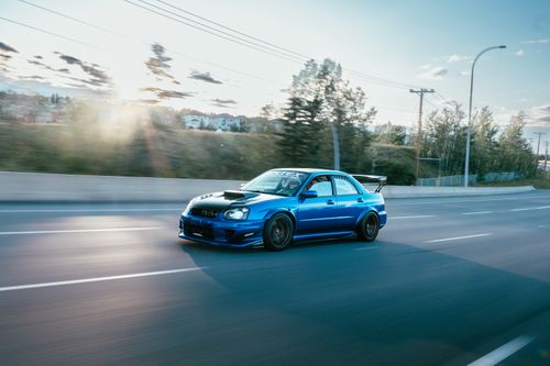 Free Dynamic shot of a blue modified Subaru WRX STI driving on a city road. Stock Photo
