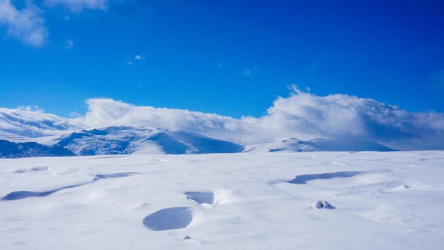 Serene snowy mountain landscape with clear blue sky, perfect for winter themes.