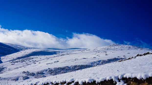 Serene view of snow-covered mountains under a vivid blue sky on a sunny winter day.