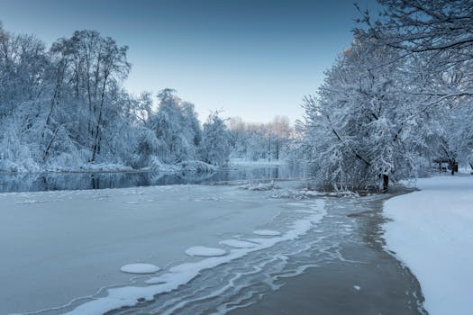 A tranquil snowy scene with icy river and frosty trees in a serene winter landscape.