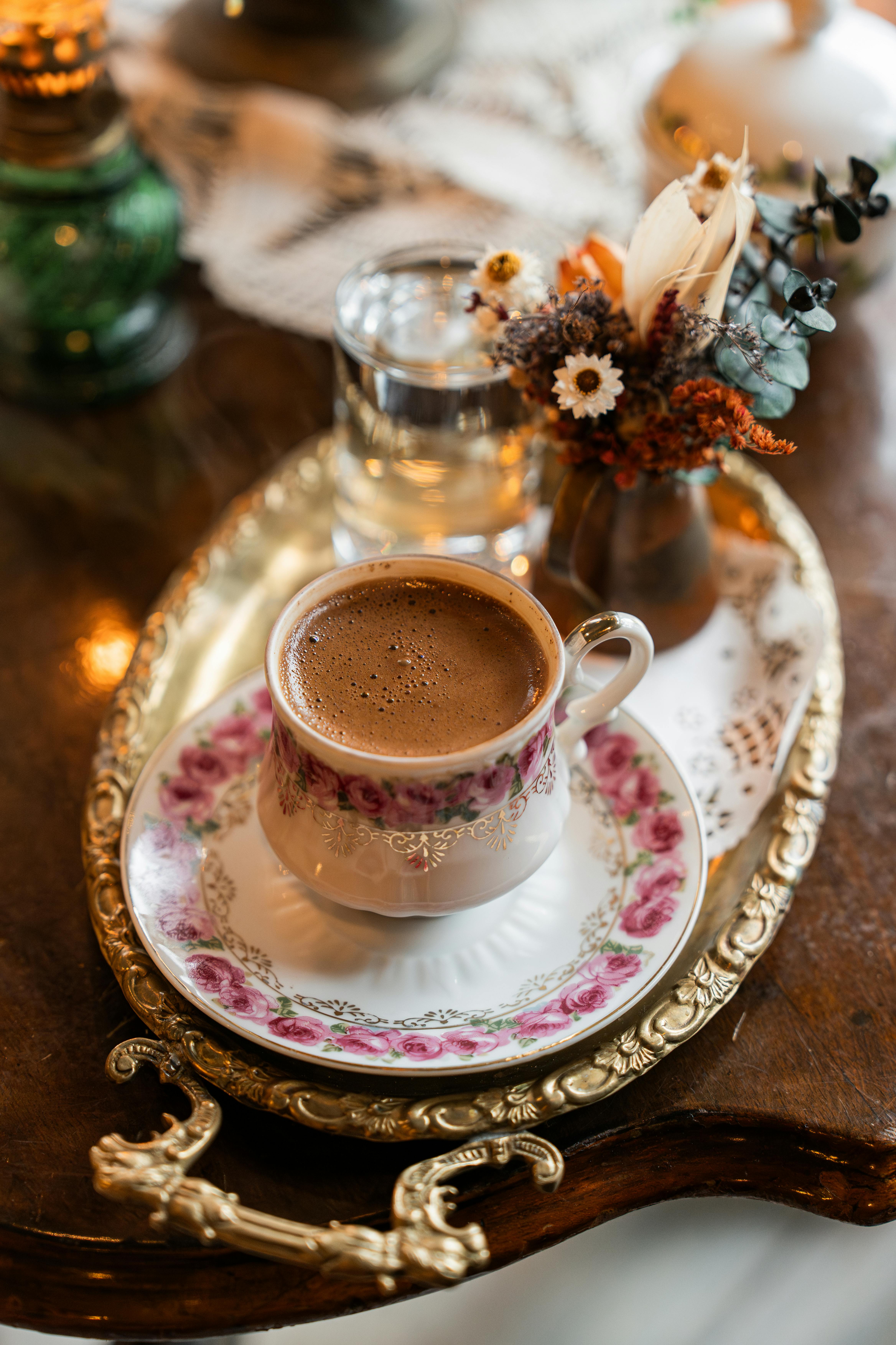A beautifully styled coffee cup with intricate floral designs on a vintage tray, evoking a warm and classic ambiance.