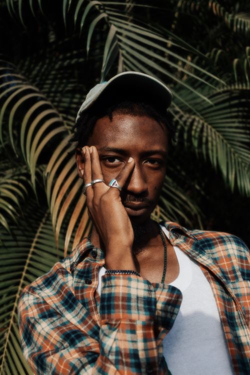 Free Striking portrait of a man in Nigeria with tropical leaves in the background, radiating style and confidence. Stock Photo