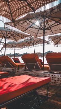 Relaxing beach scene with sunlit loungers and parasols. Ideal for summer vacation vibes.