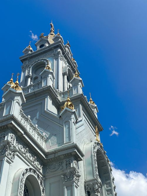 Free Stunning view of an intricate church tower with gold details under a clear blue sky. Stock Photo
