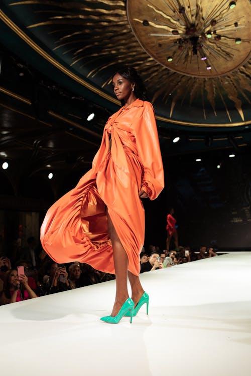 Femme En Robe à Manches Longues Orange Debout Sur Le Sol Blanc