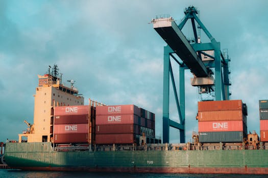 Large cargo ship loaded with colorful containers at a bustling industrial port.