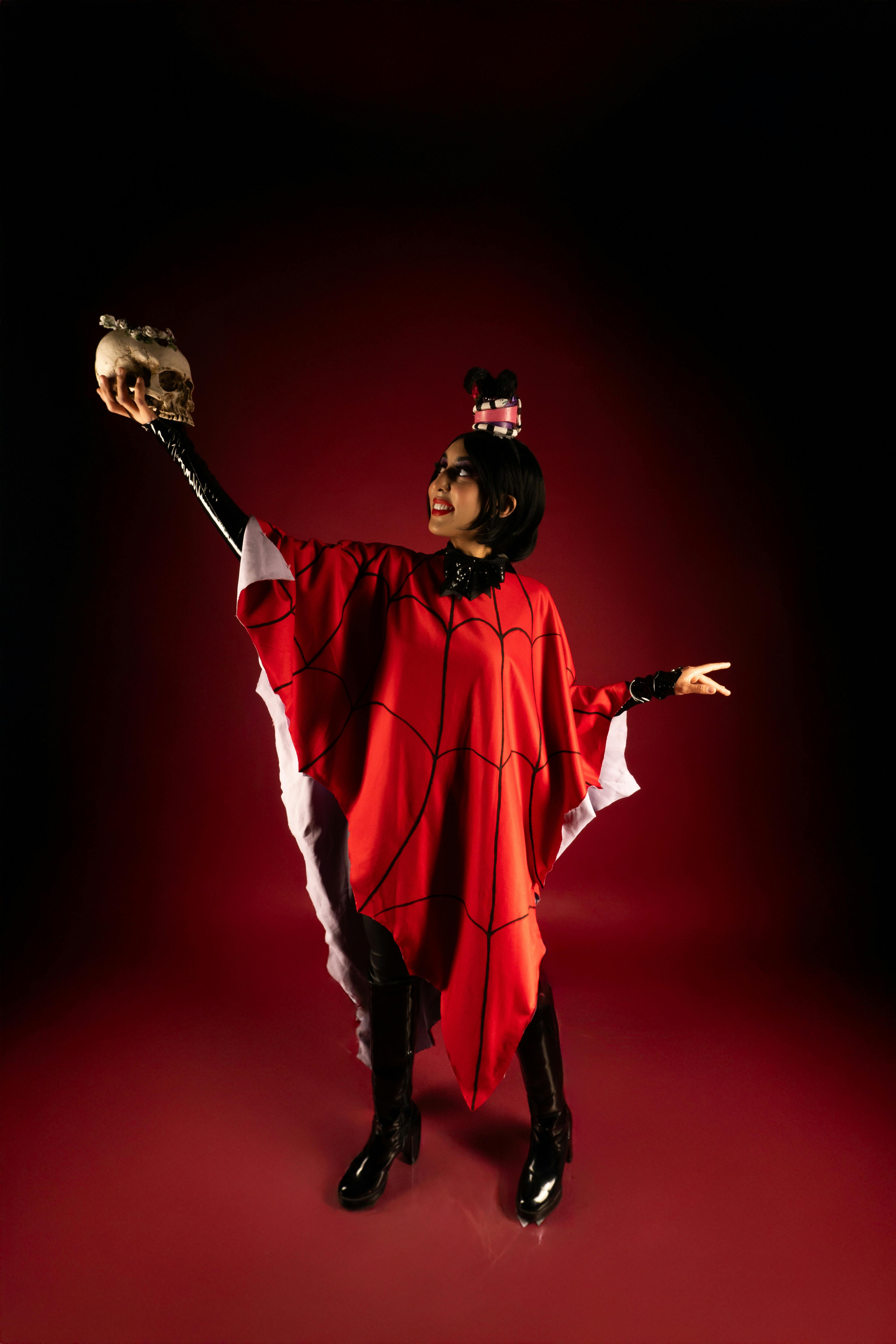 Ücretsiz Kırmızı pelerinli bir kişi, karanlık bir arka planda kafatasını tutarak dramatik bir poz veriyor ve teatral cosplay'i canlandırıyor. Stok Fotoğraflar