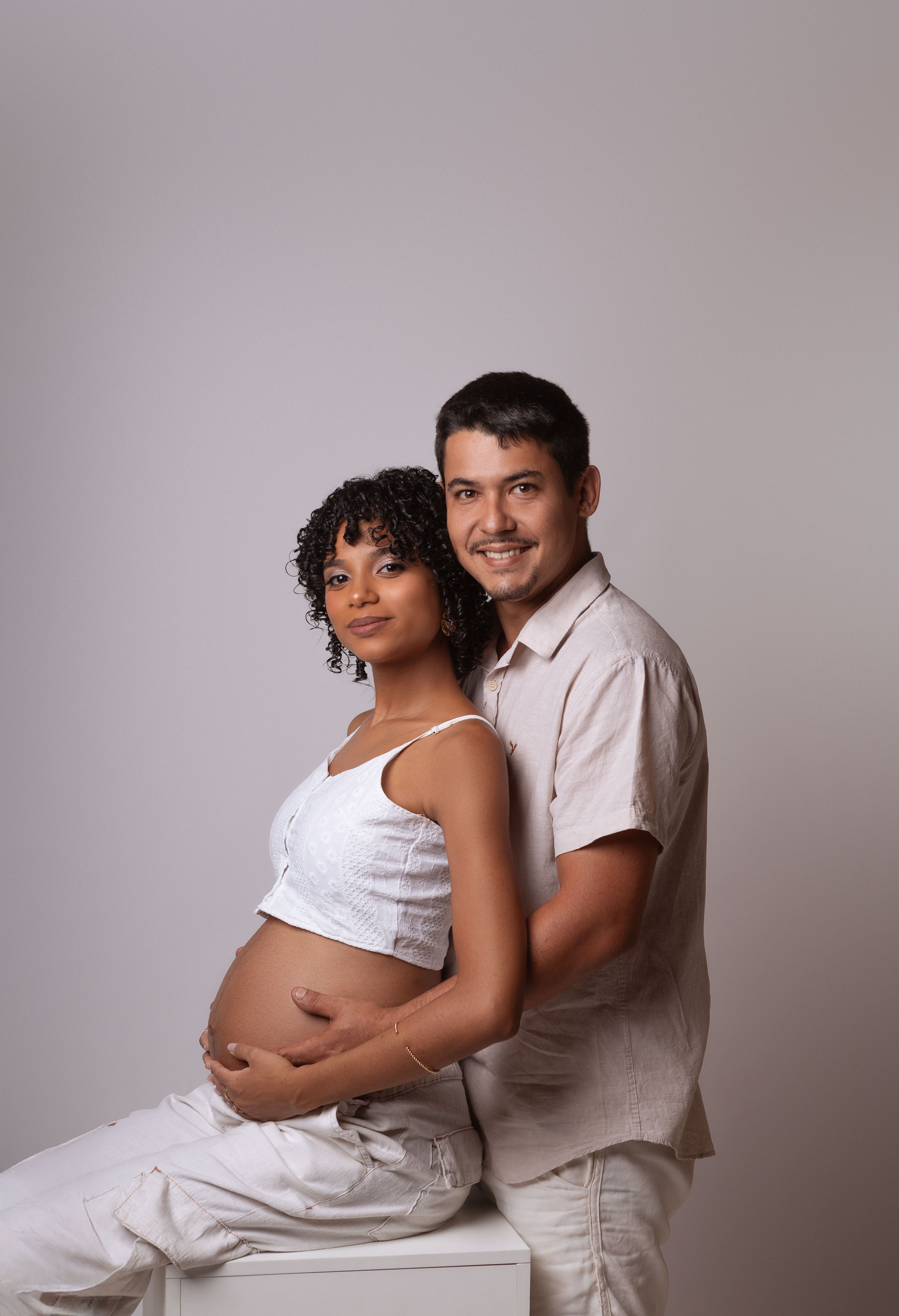 Smiling Expecting Couple Embracing Indoors · Free Stock Photo