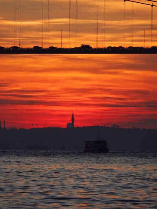 Free Dramatic sunset over Istanbul with a silhouetted bridge and skyline, reflecting on the water. Stock Photo
