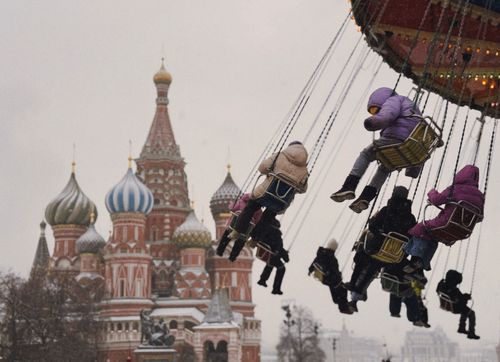 Free Festive winter scene at St. Basil's Cathedral with people on a merry-go-round in Moscow, Russia. Stock Photo