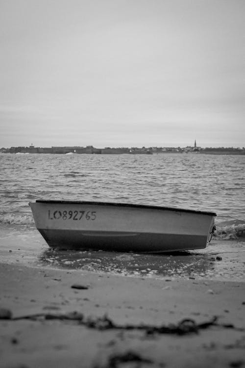 Free A lone boat rests on the beach with a calm sea in the background. Stock Photo