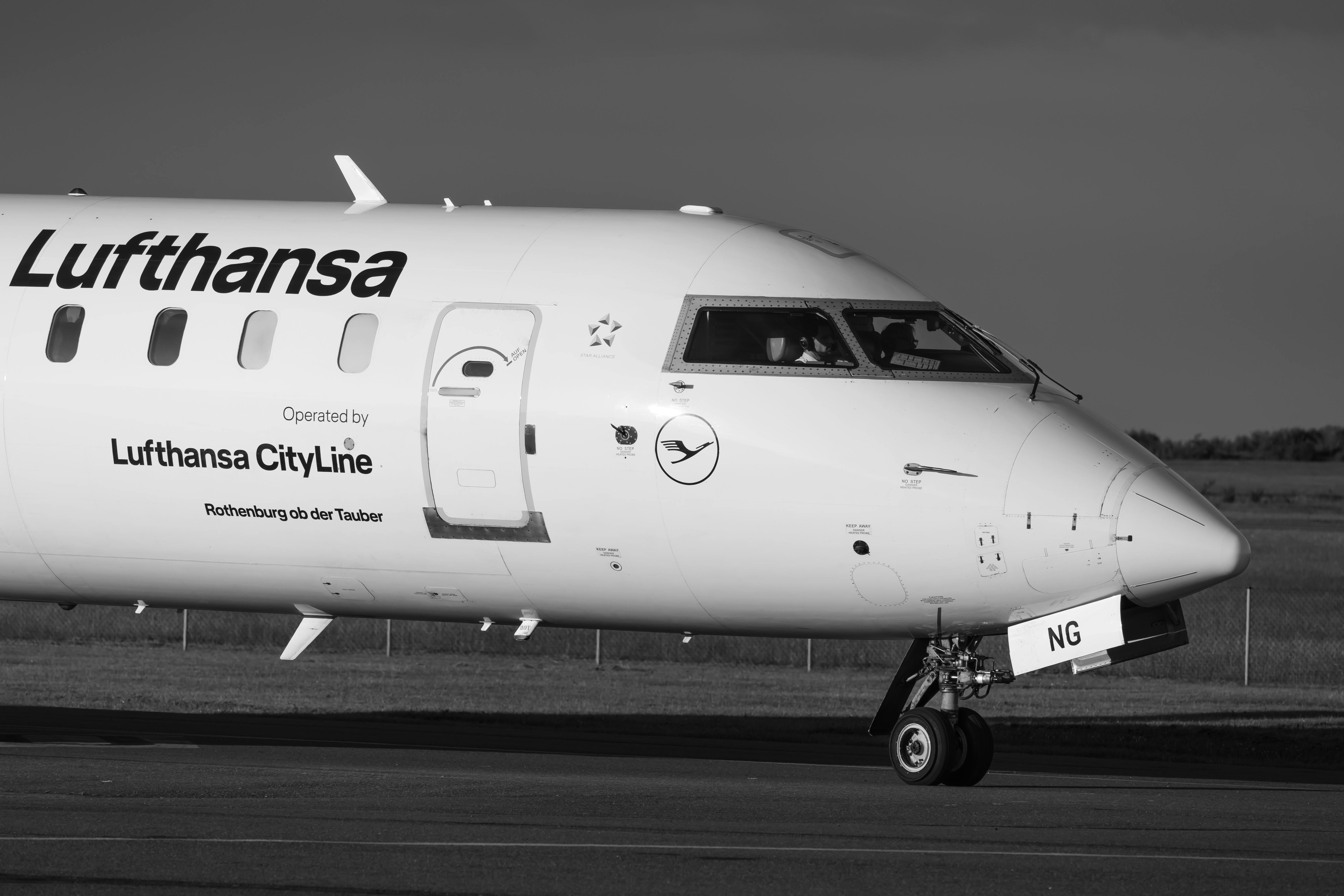 Free Black and white image of a Lufthansa CityLine aircraft taxiing on a runway. Stock Photo