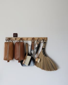 Wooden organizer holds leather bags, brush, broom, and tools.
