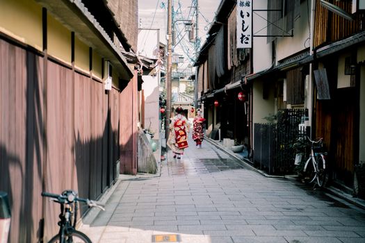在日本京都的一条历史悠久的街道上，一位穿着传统服装的艺妓正走着