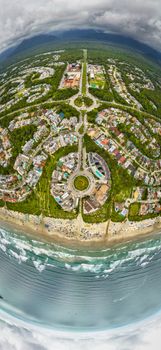 Stunning aerial shot of a coastal town with roundabout and beach, showcasing urban layout and ocean waves.