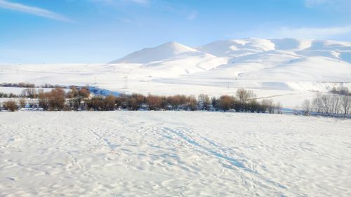 Free A serene snowy landscape featuring mountains and sparse trees under a clear blue sky. Stock Photo