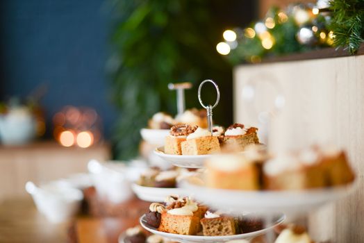 Close-up of festive cake assortment on tiered stand with bokeh lights.