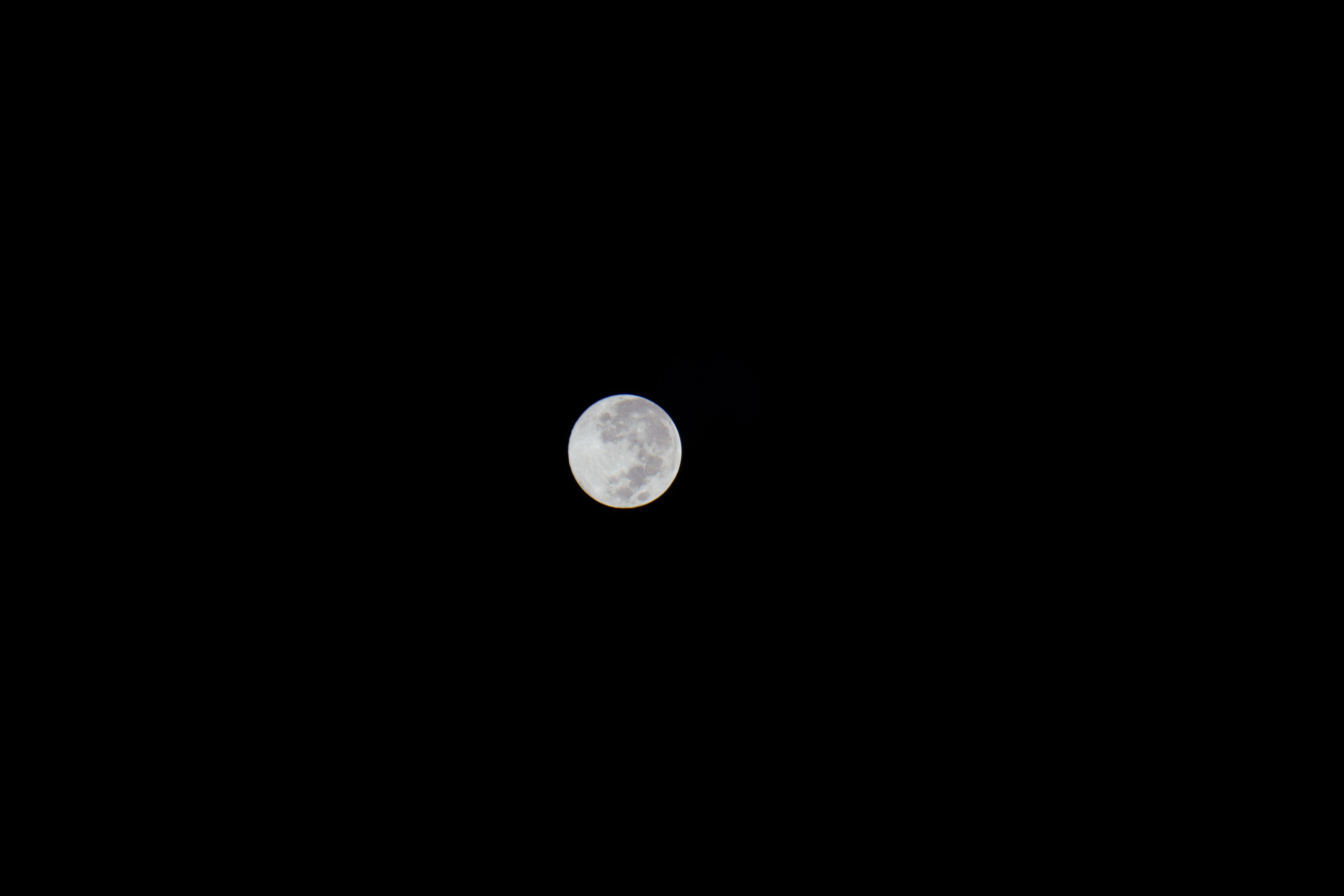 Captivating full moon on a clear night, showcasing lunar surface details against a pitch-black sky.