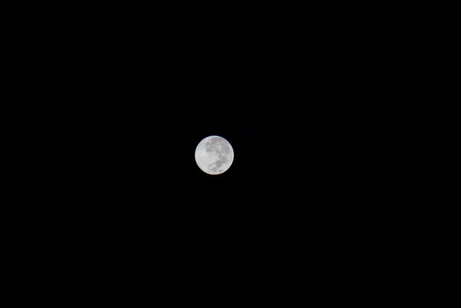Captivating full moon on a clear night, showcasing lunar surface details against a pitch-black sky.