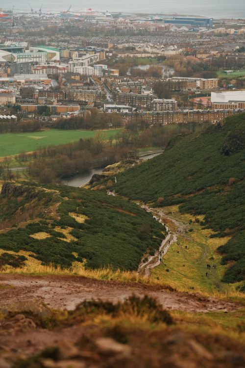 Free Picturesque view of Edinburgh from Arthur's Seat showcasing lush hills and cityscape in Scotland. Stock Photo