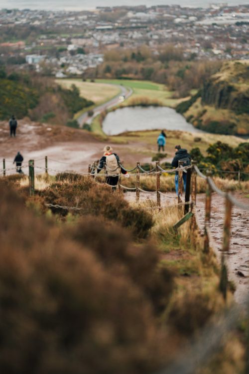 Free People walking on a scenic trail on Arthur's Seat, overlooking Edinburgh landscape. Stock Photo