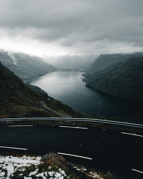 Aerial Photo of Mountains Near Body of Water Under Cloudy Sky