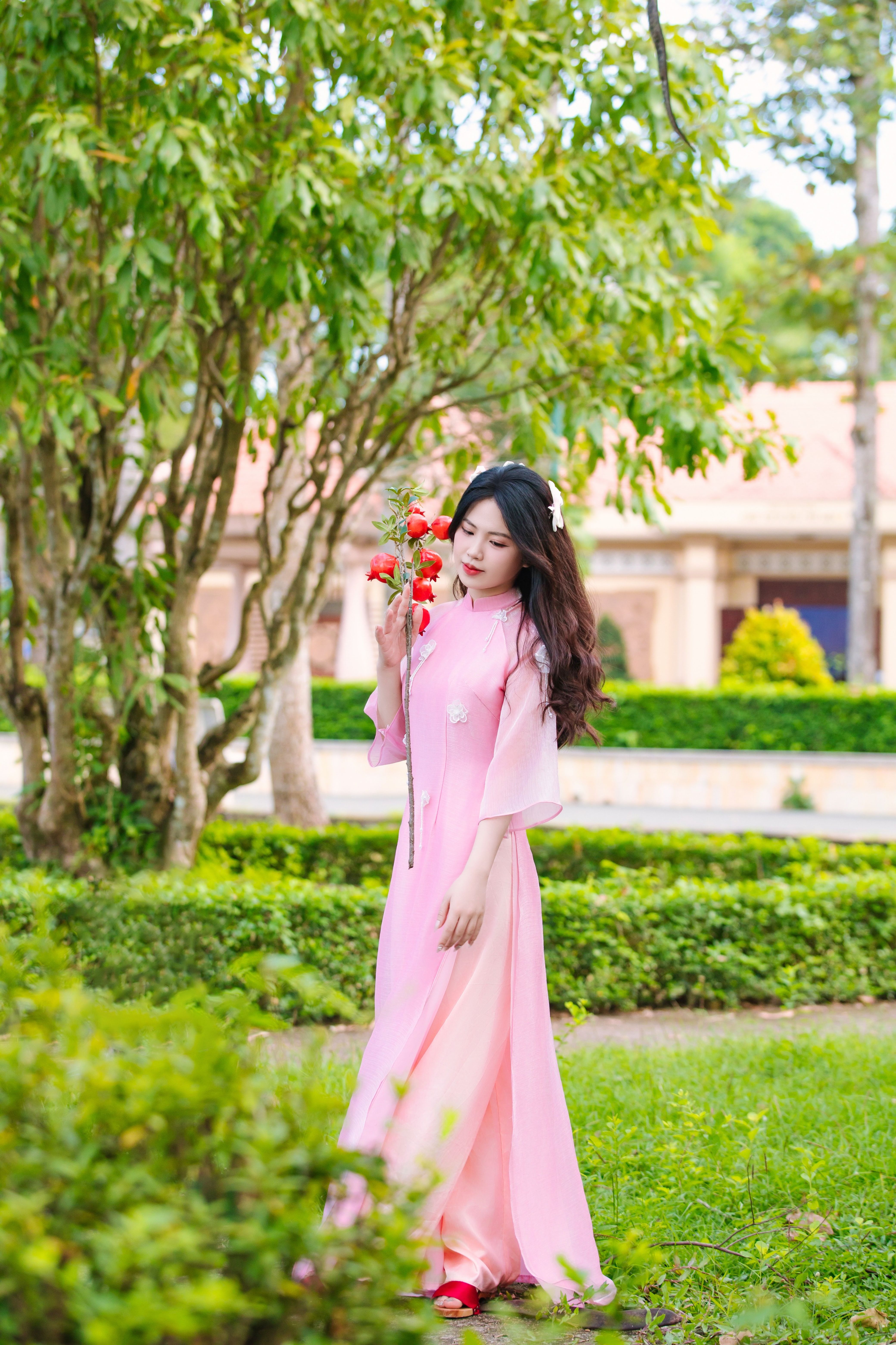 Young Woman in Pink Dress Holding Flowers Outdoors · Free Stock Photo